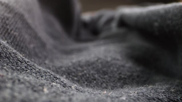 Macro shot of a camera gliding over fabric, with the weave and folds illuminated by studio lighting.
