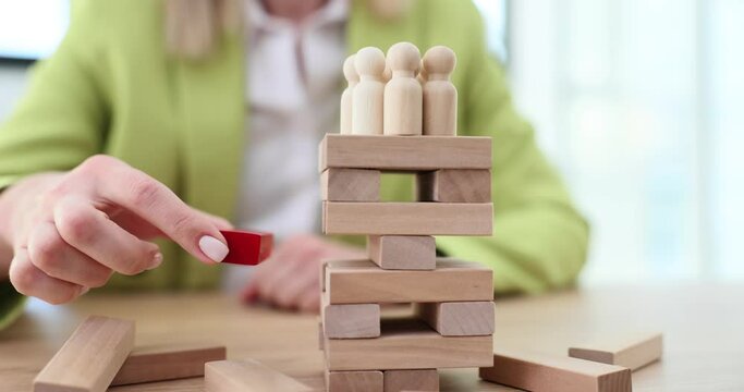 Hand taking out red wooden block from tower with crowd closeup 4k movie slow motion
