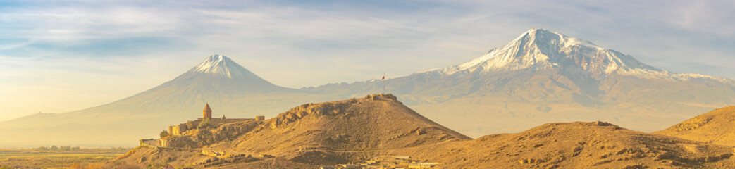Wide angle panoramic view of sunrise over Ararat mountains with the Khor Virap monastery at fall....