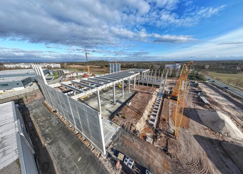 Drone image of a construction site of an industrial building with columns and beams and a heavy-duty crane