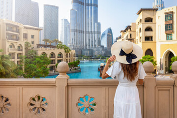 A tourist woman in a white summer dress on a sightseeing trip through Dubai downtown, United Arab...