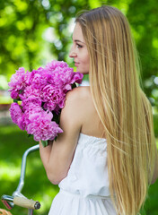 Fototapeta premium Pretty blonde girl with retro look, bike and basket with flowers