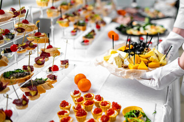 woman hands of a waiter prepare food for a buffet table in a restaurant