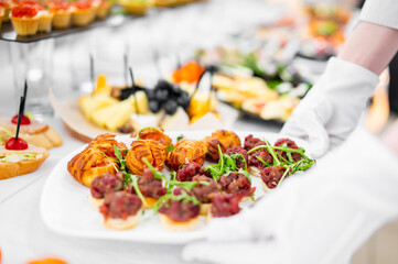 woman hands of a waiter prepare food for a buffet table in a restaurant