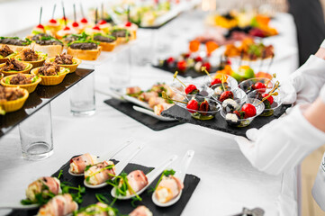 woman hands of a waiter prepare food for a buffet table in a restaurant