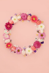 Easter wreath with decorated eggs and mini eggs  on pink background. Decorative flower garland for traditional seasonal nature floral edible food design.