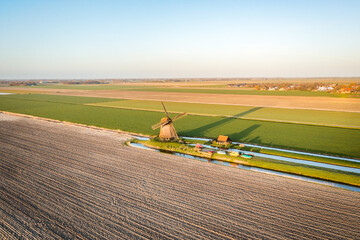 dutch windmill on a field in the countryside at sunrise