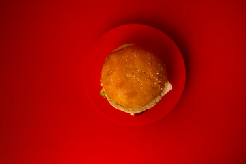  Delicious sandwich with cheese, ketchup, lettuce and cutlet is on a red round stage