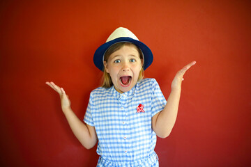 Pretty emothional children wear a hat on a red background