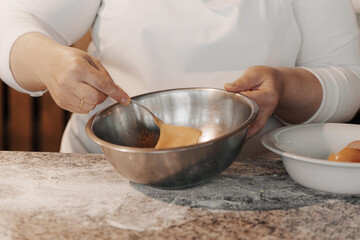 Crop anonymous female cook cracking egg into metal bowl while preparing dough for Italian pasta in kitchen