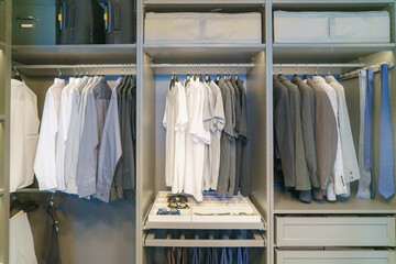 Men's suits and shirts hang in the closet..