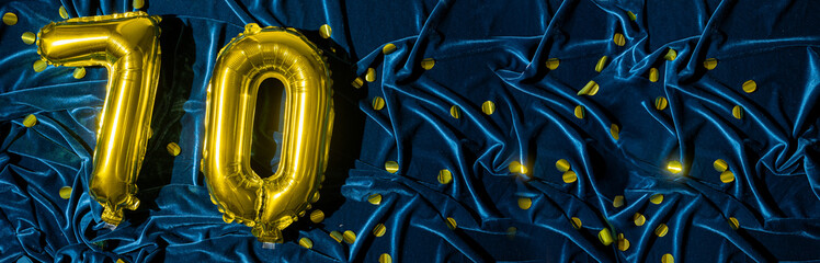 Gold foil balloon number number 70 on a background of blue velvet decoration. Birthday greeting...