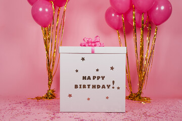 Big white surprise box with the inscription happy birthday and a bow and large bundles of pink...