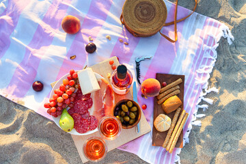 Picnic outdoor with rose wine fruits meat and cheese.