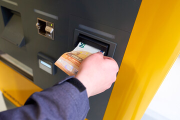 Pay the fee at the machine. Parking is expensive. Hand pushes banknote into the machine.
