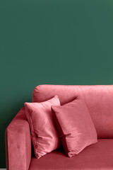 Vertical shot of red armchair with cushions in modern living room with green wall