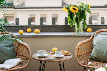 Round coffee table and two rattan armchairs with pillows on an open balcony - obrazy, fototapety, plakaty