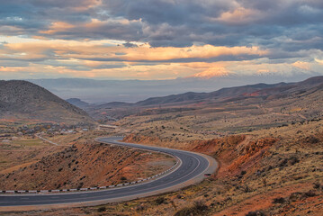 The S-curved road with Ararat mountains in the background at sunset. Travel destination Armenia