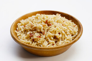 Cooked brown rice in wooden bowl on white background.