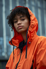 Rainy City Elegance: Mixed-Race Young Female in Orange Raincoat, Overcast Day