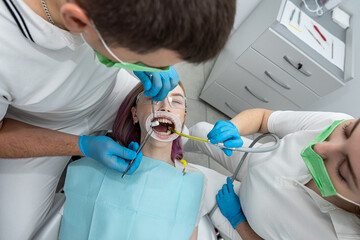patient is lying in dentistry where she is being treated by male somatologist  female assistant