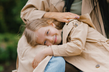 Smiling girl daughter is lying on her mother's lap. Happy childhood, caring and mother's Day - obrazy, fototapety, plakaty