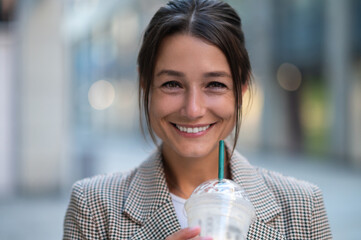 Smiling woman drinking cocktail with straw enjoys spare time background.