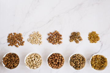 Various nuts and dried fruits in white bowls