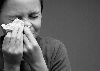 asthmatic breathing problems catching the flu child blowing nose after having a cold with grey background with people stock photo