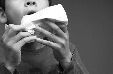 asthmatic breathing problems catching the flu child blowing nose after having a cold with grey background with people stock photo - obrazy, fototapety, plakaty