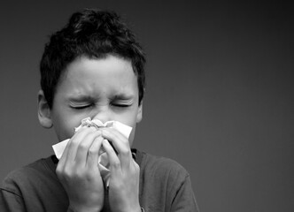 asthmatic breathing problems catching the flu child blowing nose after having a cold with grey background with people stock photo