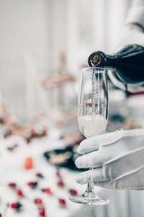 waiter pouring champagne wine from bottle in glasses