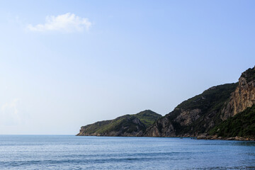 Sandy beach by the sea near Agios Georgios on the island of Corfu under a blue sky