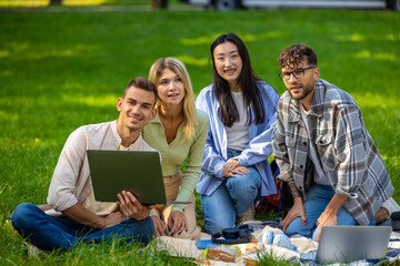 Students studying together outdoors on a green lawn