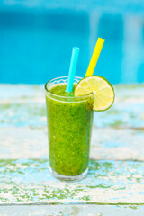Freshly blended green fruit smoothie in glass with straw