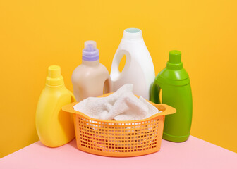 Bootleys of various sizes of laundry detergent and a laundry basket with dirty clothes.