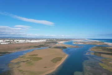 aerial drone view of climate in praia da fuseta in algarve portugal with fields, lakes and beach next to the atlantic ocean and nature