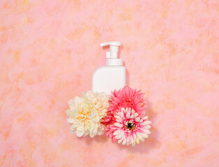 Obraz na płótnie Canvas White dishwashing gel dispenser, flowers. Flat lay.