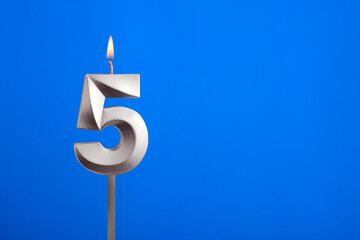 Birthday number 5 - Candle lit on blue background