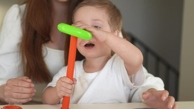 the child collects a toy pyramid. mom plays with son at home happy family. development of fine motor skills in a newborn fun child. happy family mom and baby play pyramid game. preschool education