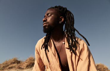 Black man with dreadlocks standing in dry field