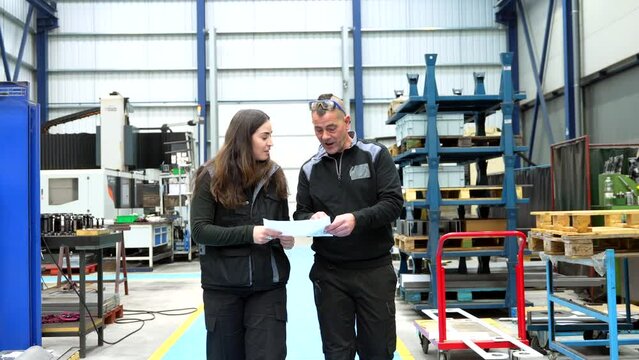 Engineers talking and looking at a paper while working in a cnc logistics factory