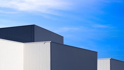 Modern black and white metal industrial factory buildings in minimal style against blue sky...