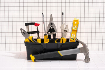 Black box with DIY tools. Hammer, screwdrivers, building level, adjustable spanner, clamps, metal shears, pliers.