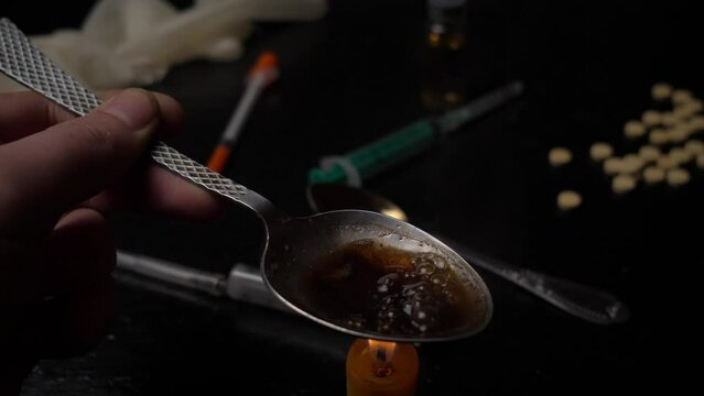 heroin addiction concept, preparing a dose for heroin injection at home on a black table