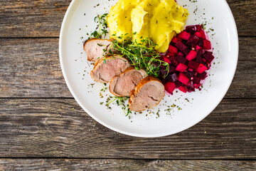 Fried pork loin with potato puree and vegetables on wooden table
