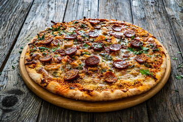 Circle pizza chorizo with chicken nuggets and mozzarella, on wooden table
