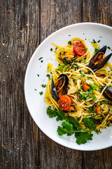 Noodles with mussels on wooden table
