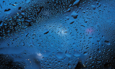 Raindrops on a clear window create a wet and rainy background.