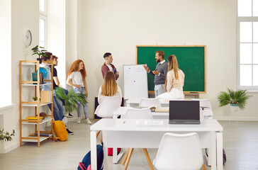 Group of school, college or university students having class in modern spacious classroom. Male...